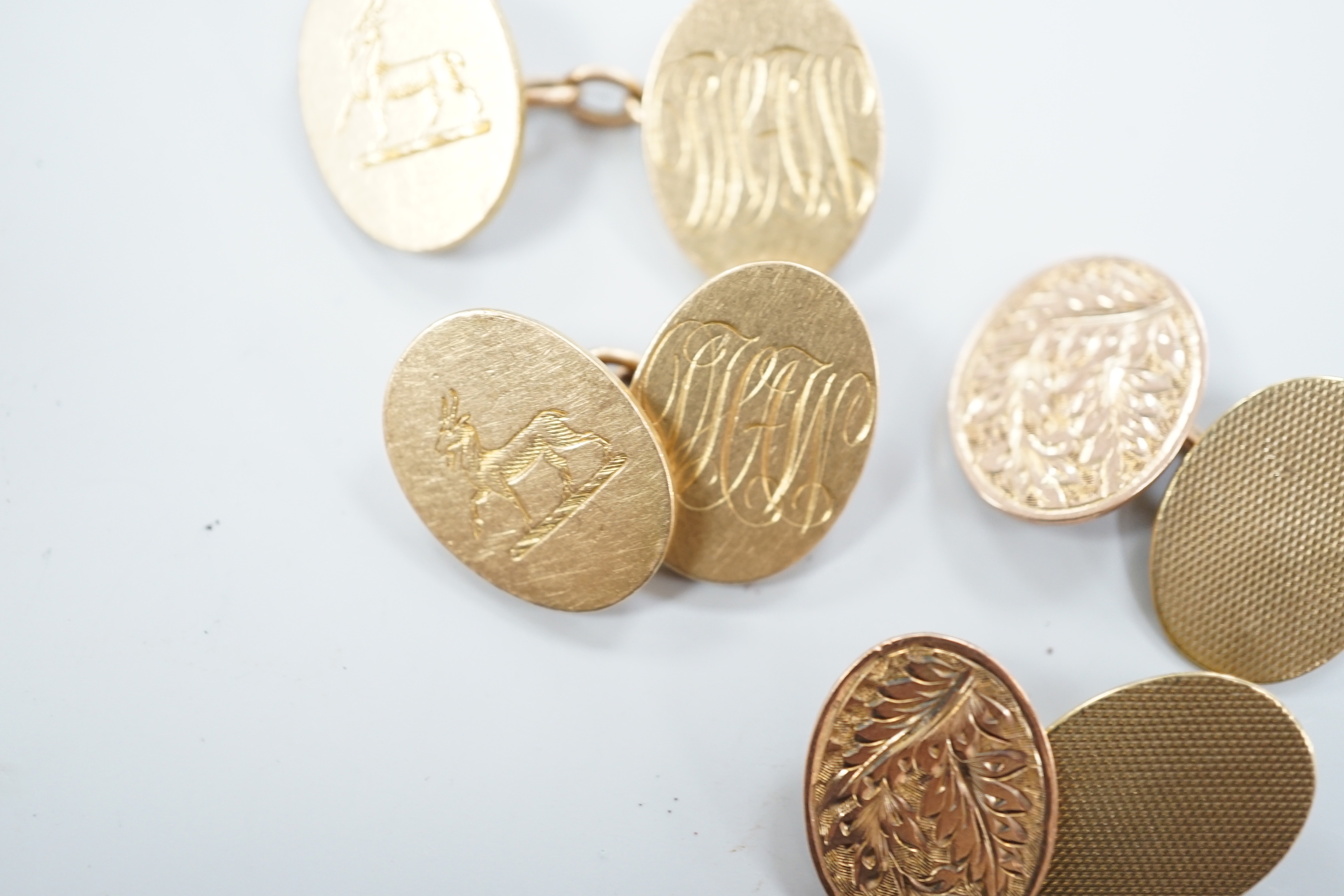 A pair of George V 18ct gold oval cufflinks, with engraved crest and initials, G.H. Johnstone & Co, Birmingham, 1915, 16.7 grams and a pair of late Victorian engraved 9ct gold oval cufflinks, 6.7 grams.